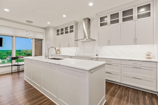 400 W 49th Ter Unit 2106, Kansas City, MO 64112 - kitchen with wall chimney exhaust hood, a sink, dark wood-style flooring, a center island with sink, and white cabinetry