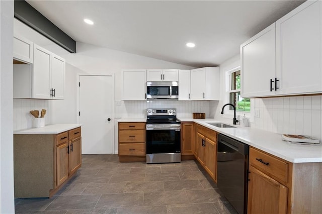 3523 Drumm Ave, Independence, MO 64055 - kitchen featuring appliances with stainless steel finishes, a sink, vaulted ceiling, decorative backsplash, and white cabinetry