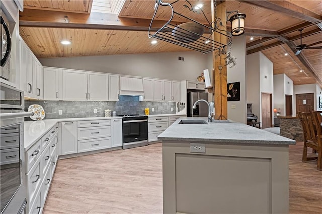 19913 Pepper Tree Rd, Edgerton, KS 66021 - kitchen featuring appliances with stainless steel finishes, a wood ceiling with exposed beams, light wood finished floors, decorative backsplash, and a kitchen island with sink