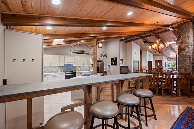 19913 Pepper Tree Rd, Edgerton, KS 66021 - kitchen featuring light wood-style floors, white cabinetry, backsplash, appliances with stainless steel finishes, and a breakfast bar