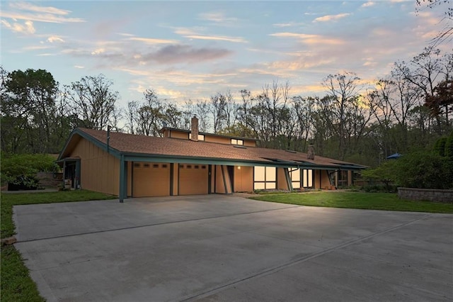 19913 Pepper Tree Rd, Edgerton, KS 66021 - view of front facade featuring an attached garage, driveway, a chimney, and a lawn
