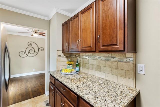 8424 Ward Parkway Plz, Kansas City, MO 64114 - kitchen with tasteful backsplash, light stone countertops, crown molding, ceiling fan, and stainless steel refrigerator