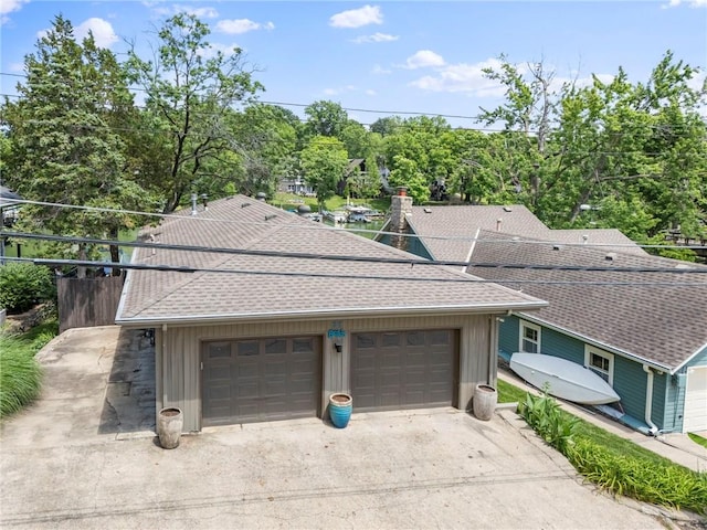 37 Beach Dr, Blue Springs, MO 64015 - view of front of house with roof with shingles, concrete driveway, board and batten siding, a garage, and view of scattered trees