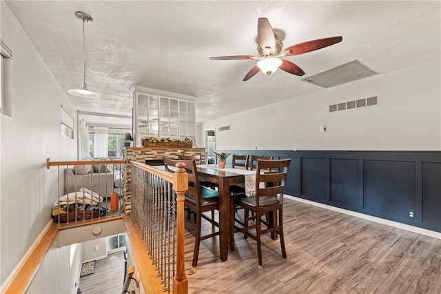37 Beach Dr, Blue Springs, MO 64015 - dining area featuring a textured ceiling, ceiling fan, wood finished floors, a wainscoted wall, and a decorative wall