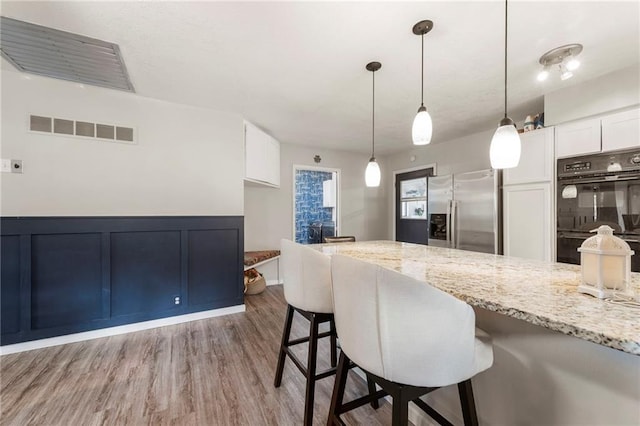 37 Beach Dr, Blue Springs, MO 64015 - kitchen featuring stainless steel fridge, light stone counters, white cabinetry, and a breakfast bar