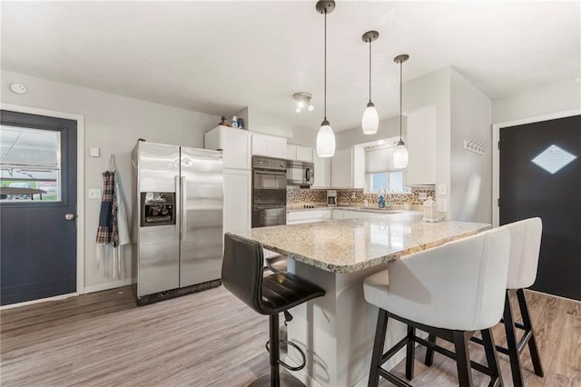 37 Beach Dr, Blue Springs, MO 64015 - kitchen featuring appliances with stainless steel finishes, light wood finished floors, a breakfast bar area, and white cabinetry