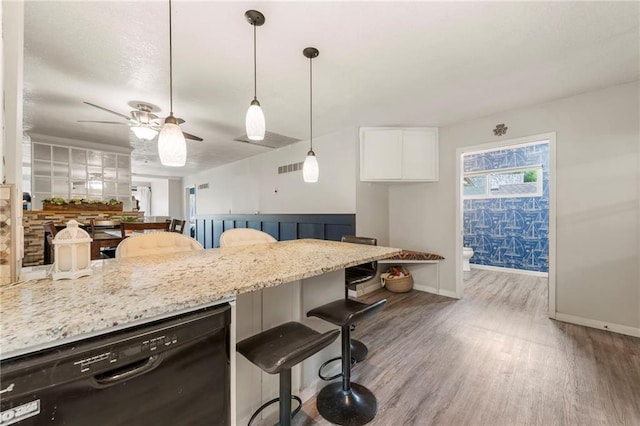 37 Beach Dr, Blue Springs, MO 64015 - kitchen with black dishwasher, a breakfast bar, wood finished floors, ceiling fan, and light stone counters
