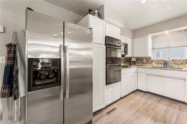 37 Beach Dr, Blue Springs, MO 64015 - kitchen with black appliances, a sink, white cabinets, light stone counters, and decorative backsplash