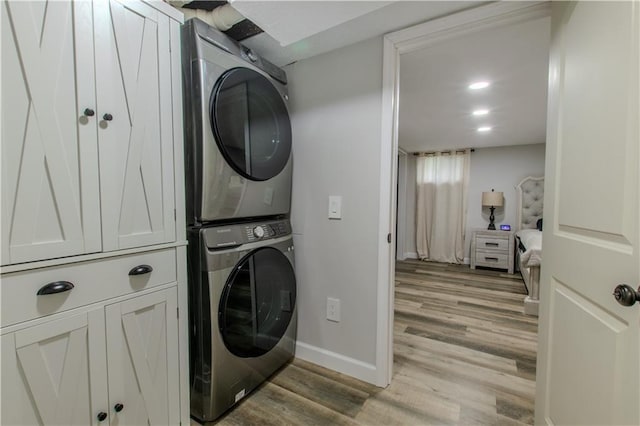604 Lake Rd, Garden City, MO 64747 - laundry area featuring stacked washer / dryer, light wood-type flooring, baseboards, and cabinet space