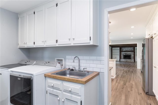 10246 Russell St, Overland Park, KS 66212 - laundry room with cabinet space, separate washer and dryer, light wood-type flooring, a fireplace, and recessed lighting