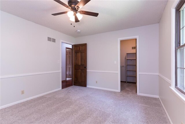 10246 Russell St, Overland Park, KS 66212 - unfurnished bedroom featuring a walk in closet, carpet flooring, and multiple windows