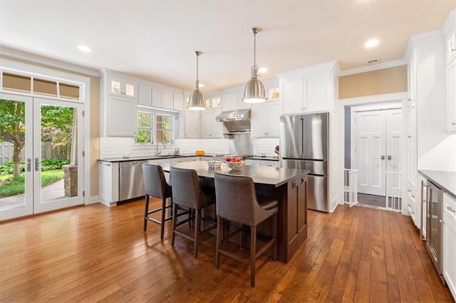 5812 Reinhardt Dr, Fairway, KS 66205 - kitchen featuring appliances with stainless steel finishes, a breakfast bar, dark wood-style floors, a center island, and ornamental molding