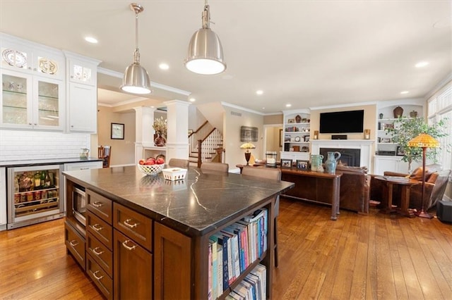 5812 Reinhardt Dr, Fairway, KS 66205 - kitchen featuring wine cooler, light wood finished floors, a warm lit fireplace, white cabinetry, and glass insert cabinets