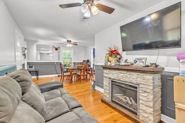 8303 Wabash Ave, Kansas City, MO 64132 - living room with a ceiling fan, light wood-style floors, a wainscoted wall, and a fireplace