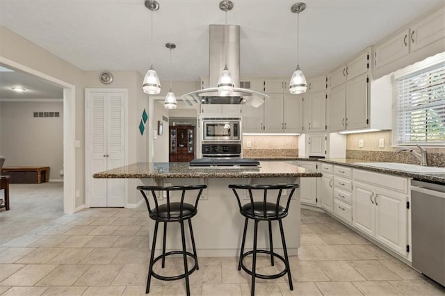 8410 W 117th St, Overland Park, KS 66210 - kitchen with appliances with stainless steel finishes, a center island, decorative backsplash, a kitchen breakfast bar, and white cabinetry