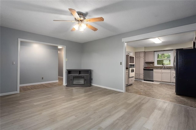 10203 Outer Rd, Odessa, MO 64076 - unfurnished living room with light wood finished floors, ceiling fan, and a textured ceiling