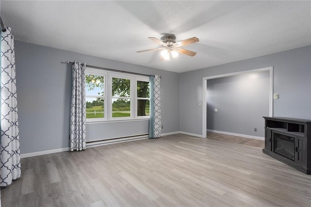 10203 Outer Rd, Odessa, MO 64076 - unfurnished living room with baseboard heating, a ceiling fan, wood finished floors, and a textured ceiling