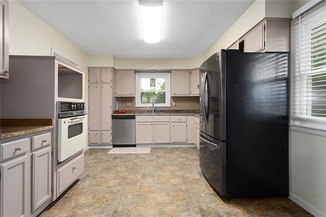 10203 Outer Rd, Odessa, MO 64076 - kitchen featuring black fridge with ice dispenser, stainless steel dishwasher, white oven, stone finish floors, and backsplash