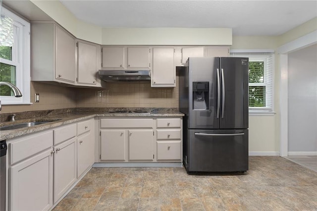 10203 Outer Rd, Odessa, MO 64076 - kitchen with appliances with stainless steel finishes, under cabinet range hood, decorative backsplash, and stone finish flooring