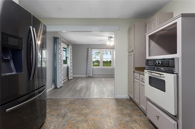 10203 Outer Rd, Odessa, MO 64076 - kitchen with fridge with ice dispenser, white oven, stone finish floors, and ceiling fan