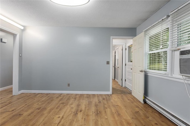 10203 Outer Rd, Odessa, MO 64076 - unfurnished room featuring a baseboard heating unit, light wood-style floors, and a textured ceiling