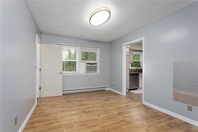 10203 Outer Rd, Odessa, MO 64076 - spare room featuring baseboard heating, light wood-style flooring, cooling unit, and a textured ceiling