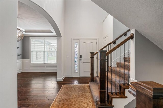 16154 S Canton St, Gardner, KS 66030 - foyer entrance featuring arched walkways, hardwood / wood-style floors, stairs, a textured ceiling, and a wainscoted wall