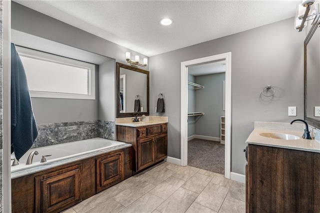 16154 S Canton St, Gardner, KS 66030 - bathroom featuring two vanities, a garden tub, a spacious closet, and a textured ceiling