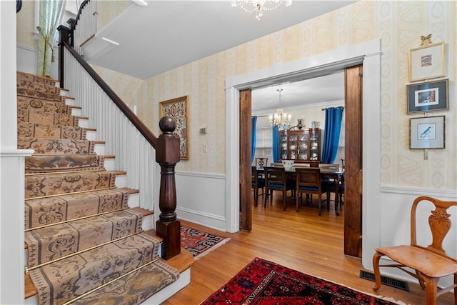 1809 Main St, Lexington, MO 64067 - stairs featuring wallpapered walls, a chandelier, wainscoting, and wood finished floors