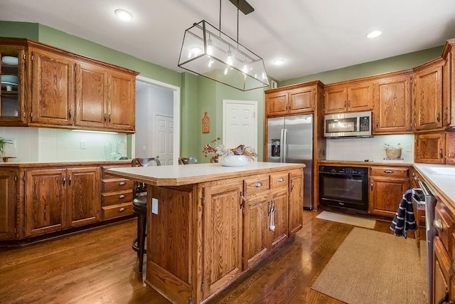 14810 W 72nd St, Shawnee, KS 66216 - kitchen with stainless steel appliances, a center island, dark wood-type flooring, brown cabinets, and recessed lighting