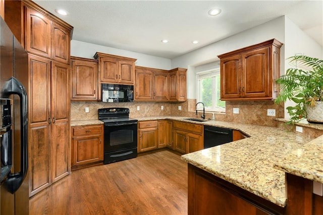 21835 W 175th Ter, Olathe, KS 66062 - kitchen with black appliances, wood finished floors, light stone countertops, a peninsula, and recessed lighting