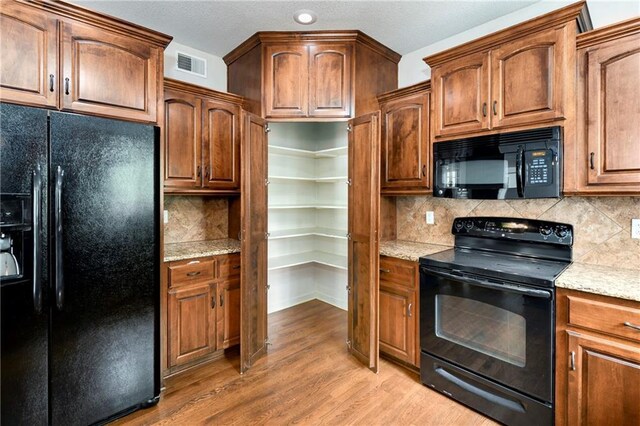 21835 W 175th Ter, Olathe, KS 66062 - kitchen with black appliances, light wood-style flooring, tasteful backsplash, light stone counters, and recessed lighting