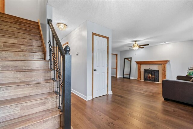 8604 NE 72nd Ter, Kansas City, MO 64158 - staircase with a ceiling fan, a fireplace, wood finished floors, baseboards, and a textured ceiling
