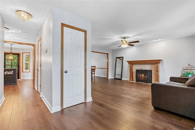 8604 NE 72nd Ter, Kansas City, MO 64158 - living area with wood finished floors, a ceiling fan, a tile fireplace, baseboards, and a textured ceiling