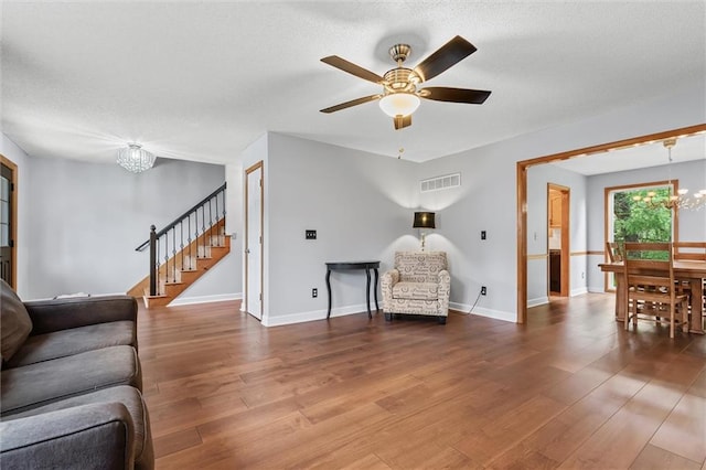8604 NE 72nd Ter, Kansas City, MO 64158 - living area featuring a chandelier, stairs, wood finished floors, a ceiling fan, and a textured ceiling