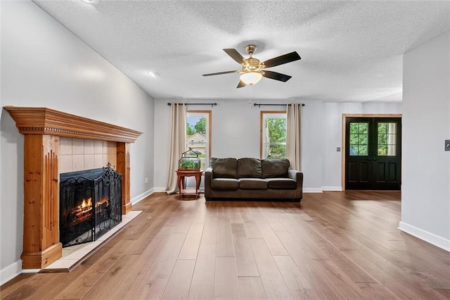 8604 NE 72nd Ter, Kansas City, MO 64158 - living room featuring a tile fireplace, a ceiling fan, baseboards, wood finished floors, and a textured ceiling
