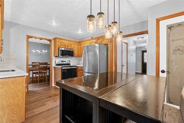 8604 NE 72nd Ter, Kansas City, MO 64158 - kitchen with appliances with stainless steel finishes, a chandelier, a sink, backsplash, and light wood-style floors