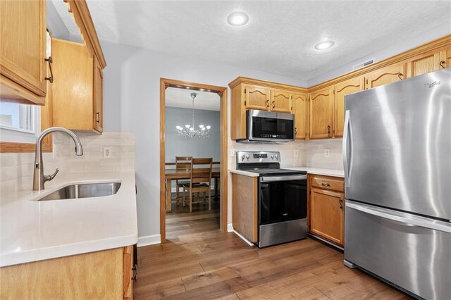 8604 NE 72nd Ter, Kansas City, MO 64158 - kitchen featuring appliances with stainless steel finishes, a sink, tasteful backsplash, light countertops, and wood finished floors