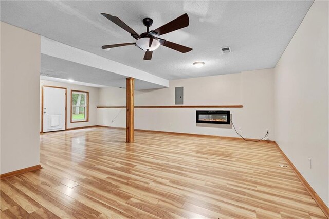 8604 NE 72nd Ter, Kansas City, MO 64158 - unfurnished living room with electric panel, wood finished floors, a glass covered fireplace, a textured ceiling, and baseboards