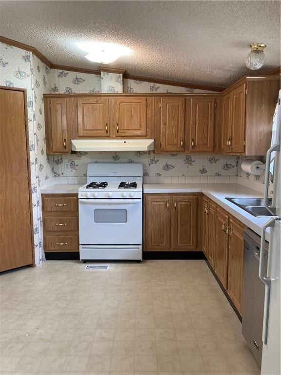 2000 E 19th St Unit 5, Lawrence, KS 66046 - kitchen with white gas range, under cabinet range hood, wallpapered walls, crown molding, and a textured ceiling