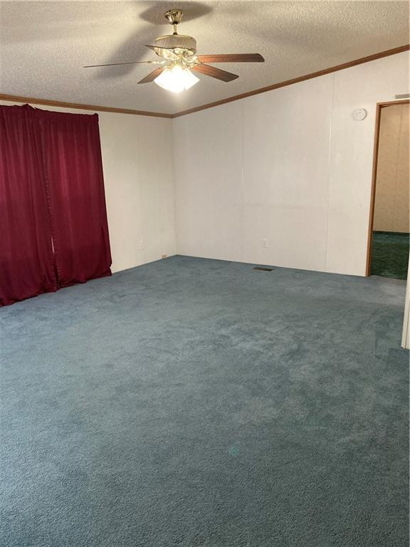 2000 E 19th St Unit 5, Lawrence, KS 66046 - unfurnished room featuring ornamental molding, a ceiling fan, a textured ceiling, and carpet flooring