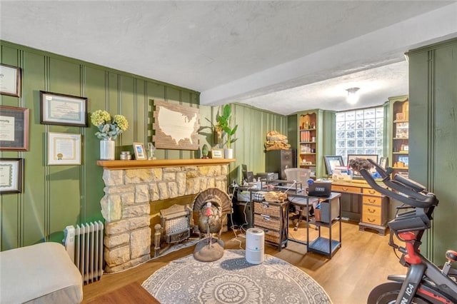 617 E 64th Ter, Kansas City, MO 64131 - home office with radiator heating unit, wood finished floors, a textured ceiling, and a fireplace