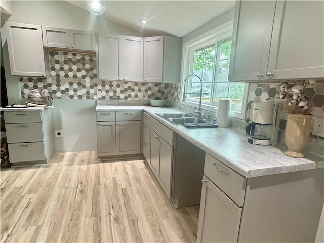 10057 Otter Rd, Clinton, MO 64735 - kitchen with a sink, light wood finished floors, decorative backsplash, vaulted ceiling, and light countertops