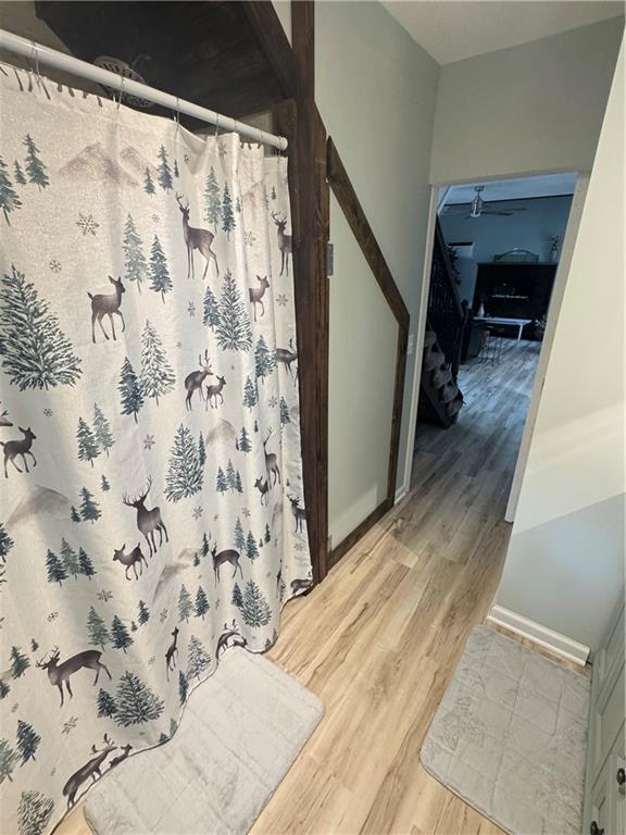 10057 Otter Rd, Clinton, MO 64735 - full bathroom with wood finished floors, a shower with curtain, and baseboards