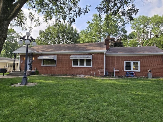 8716 E 74th St, Kansas City, MO 64133 - rear view of house featuring brick siding, a yard, a shingled roof, and a chimney