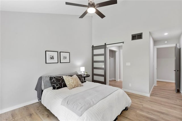 11917 W 66th St, Shawnee, KS 66216 - bedroom with a barn door, light wood finished floors, a high ceiling, and ceiling fan