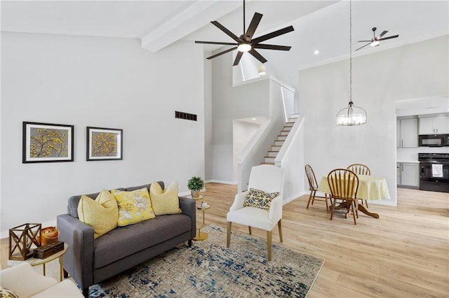 11917 W 66th St, Shawnee, KS 66216 - living room with stairway, a ceiling fan, a high ceiling, a chandelier, and light wood-type flooring