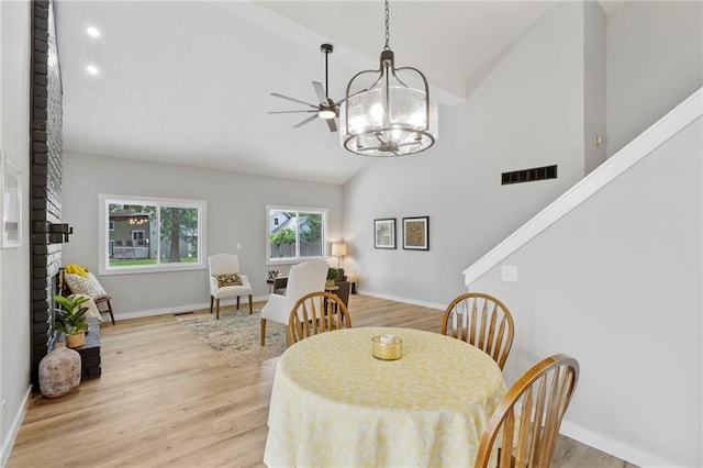 11917 W 66th St, Shawnee, KS 66216 - dining area with light wood-style flooring, high vaulted ceiling, a chandelier, recessed lighting, and a brick fireplace
