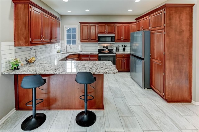 3403 E Devonshire Dr, Saint Joseph, MO 64506 - kitchen featuring appliances with stainless steel finishes, a peninsula, decorative backsplash, light stone counters, and a sink
