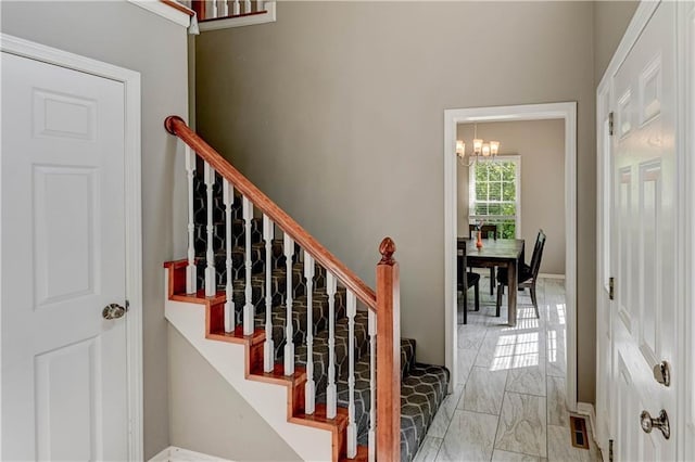 3403 E Devonshire Dr, Saint Joseph, MO 64506 - staircase with marble look tiles, a chandelier, and baseboards